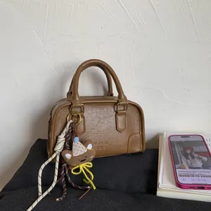 Detail of coffee brown Boston bag with lychee texture and cute bear plush charm