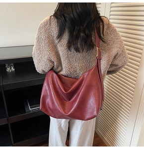 Burgundy large capacity soft leather tote bag worn by a model in a cozy indoor setting