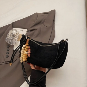Detail of black crescent shoulder bag with colorful retro wooden bead charms on coat