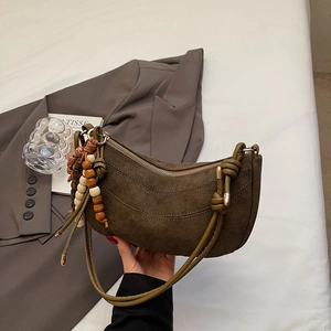 Detail of suede crescent bag with olive knot handle and colorful wooden beads