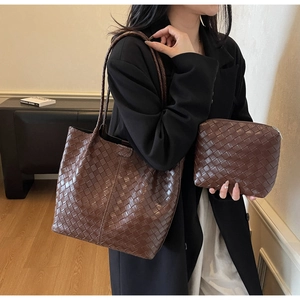 Detail shot of dark brown woven leather tote with matching zipper pouch and long handles