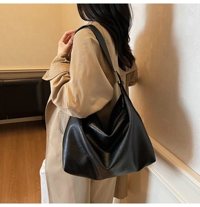 Lifestyle shot of a black leather Hobo bag worn over a trench coat for chic commuting