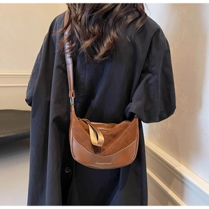Borsa a tracolla marrone a mezzaluna in pelle mista indossata su un cappotto nero elegante