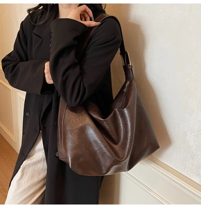 Detail of deep brown retro leather hobo bag showing texture and golden buckle on model