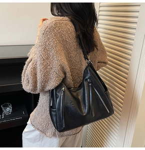 Close-up of black leather hobo bag with fringe zippers and soft grain texture