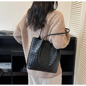 Close-up of black woven tote bag texture featuring large capacity and leather straps