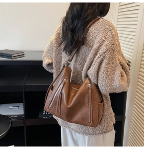 Detail view of brown leather hobo bag with tassel zippers on model for daily commute