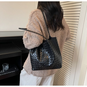 Detail view of the black woven leather tote bag with classic weave texture and long straps