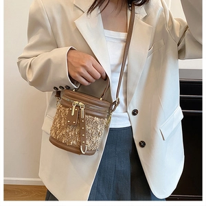 Detail einer Mini-Eimertasche aus braunem Leder und Tweed, getragen von einem Modell