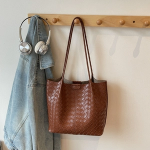 Close-up of brown woven tote bag hanging on a hook with high quality leather texture