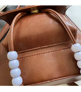 Detail of vintage brown leather backpack with drawstring closure and white pearl accents