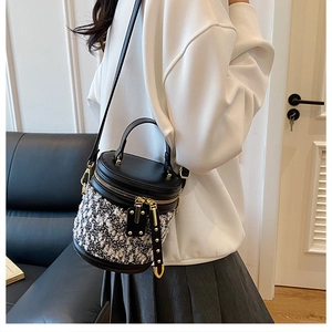 Detailansicht einer zweifarbigen Beuteltasche mit Tweed-Struktur und Goldreißverschluss