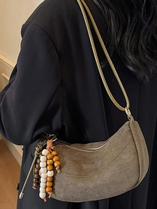 Retro taupe suede crescent hobo bag with ethnic wooden bead charm worn by a model