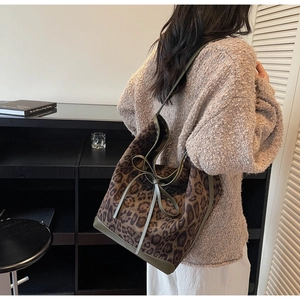 Detail of trendy leopard print bucket bag with olive leather trim and bow accent