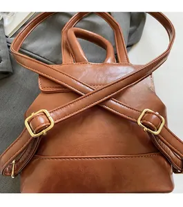 Detail view of vintage brown leather backpack showing gold hardware and strap texture