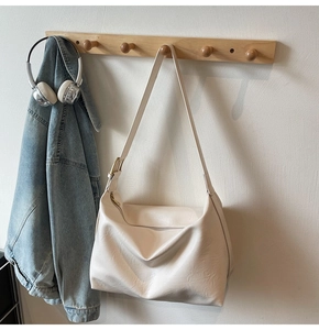 Close-up of the adjustable strap and zipper detail on this cream leather tote bag