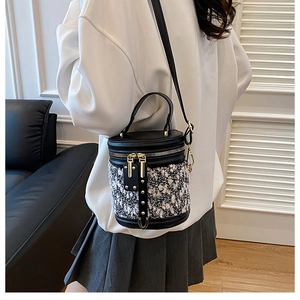 Detail einer Beuteltasche aus Tweed und schwarzem Leder mit goldener Hardware