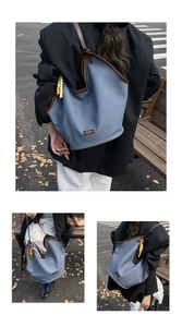 Macro shot of large blue canvas tote bag with brown leather trim and beaded detail
