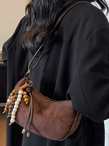 Brown suede hobo bag with ethnic beaded tassel charm and black minimalist shoulder strap