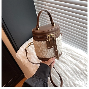 Detail einer braunen Leder- und beigen Tweed-Beuteltasche mit Reißverschluss und Griff