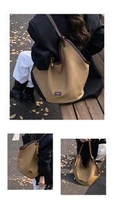 Detail of khaki canvas tote bag with dark coffee leather trim and beaded pendant ornament