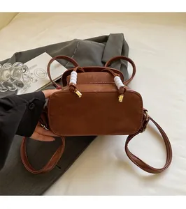 Detail view of brown leather backpack handle with white bead accents and gold buckles