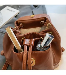 Detail showing brown leather bucket backpack with herringbone lining and front magnetic pocket