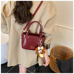 Détail du sac seau bordeaux avec garniture dorée polie et pendentif ours en peluche mignon
