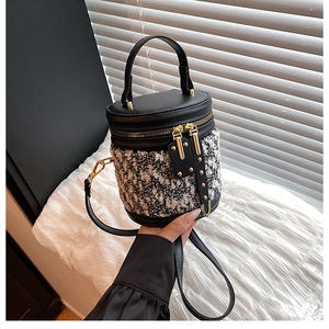 Detailaufnahme der Tweed-Zylindertasche mit Goldreißverschlüssen und Lederbesatz