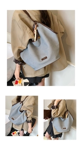 Detail view of large canvas tote bag with brown leather trim and wooden bead charm