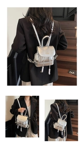 Detail view of silver metallic mini backpack featuring pearl drawstring charms and brand logo