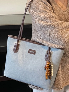 Minimalist canvas tote bag with brown leather handles and colorful beaded charm