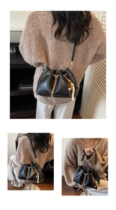 Detail showing a black drawstring bucket bag with colorful bead tassel and gold hardware
