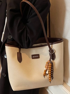 Chic beige canvas tote bag with brown leather trim and retro wooden bead pendant