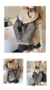 Close-up of gray vintage textured tote bag with black trim and sleek leather shoulder strap