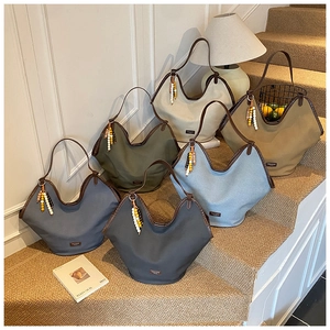 Collection of large canvas tote bags with leather trim and colorful bead charms on stairs
