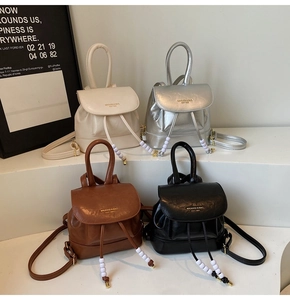 Mini vintage backpacks in cream, silver, brown, and black with beaded drawstring details