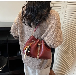 Detail of vintage burgundy bucket bag with chain drawstring and ethnic beaded tassel