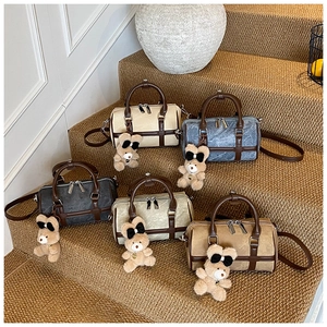 Cinco bolsos tipo boston en varios colores en una escalera con lindos colgantes de oso