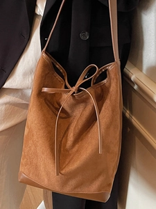 Brown suede bucket bag with leather trim and drawstring bow for a vintage chic look