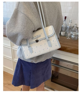 Detail showing the light blue floral jacquard texture and bow decor of the shoulder bag