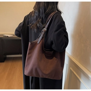Detail of soft matte brown suede tote bag with adjustable silver buckle strap on shoulder