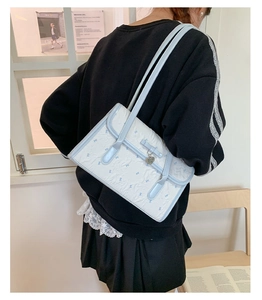 Detail of light blue bow pattern bag with metallic heart charm and pleated texture