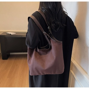 Close-up of a large brown suede tote bag with leather straps worn by a model