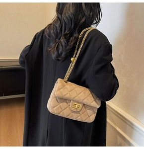 Dettaglio borsa a tracolla trapuntata in camoscio marrone chiaro con catena oro su modella