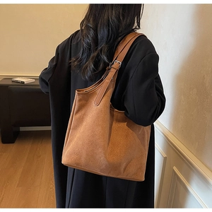 Close-up of a vintage brown suede tote bag with adjustable shoulder strap on model