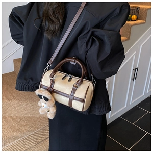 Detalle del bolso boston beige con correas de cuero marrón y colgante de oso de peluche