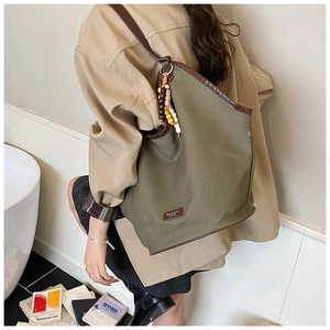 Olive green canvas hobo bag with brown leather straps and wooden bead charm detail