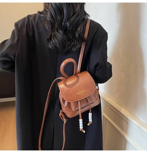 Detail of brown faux leather backpack with white bead drawstrings and gold logo