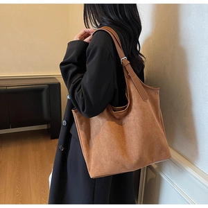 Close-up of a large brown suede tote bag featuring adjustable straps and minimalist design